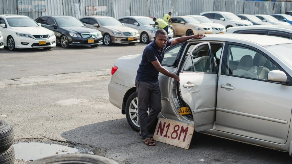 Nigerian car buyer closely inspecting the door seam of a used sedan for accident damage